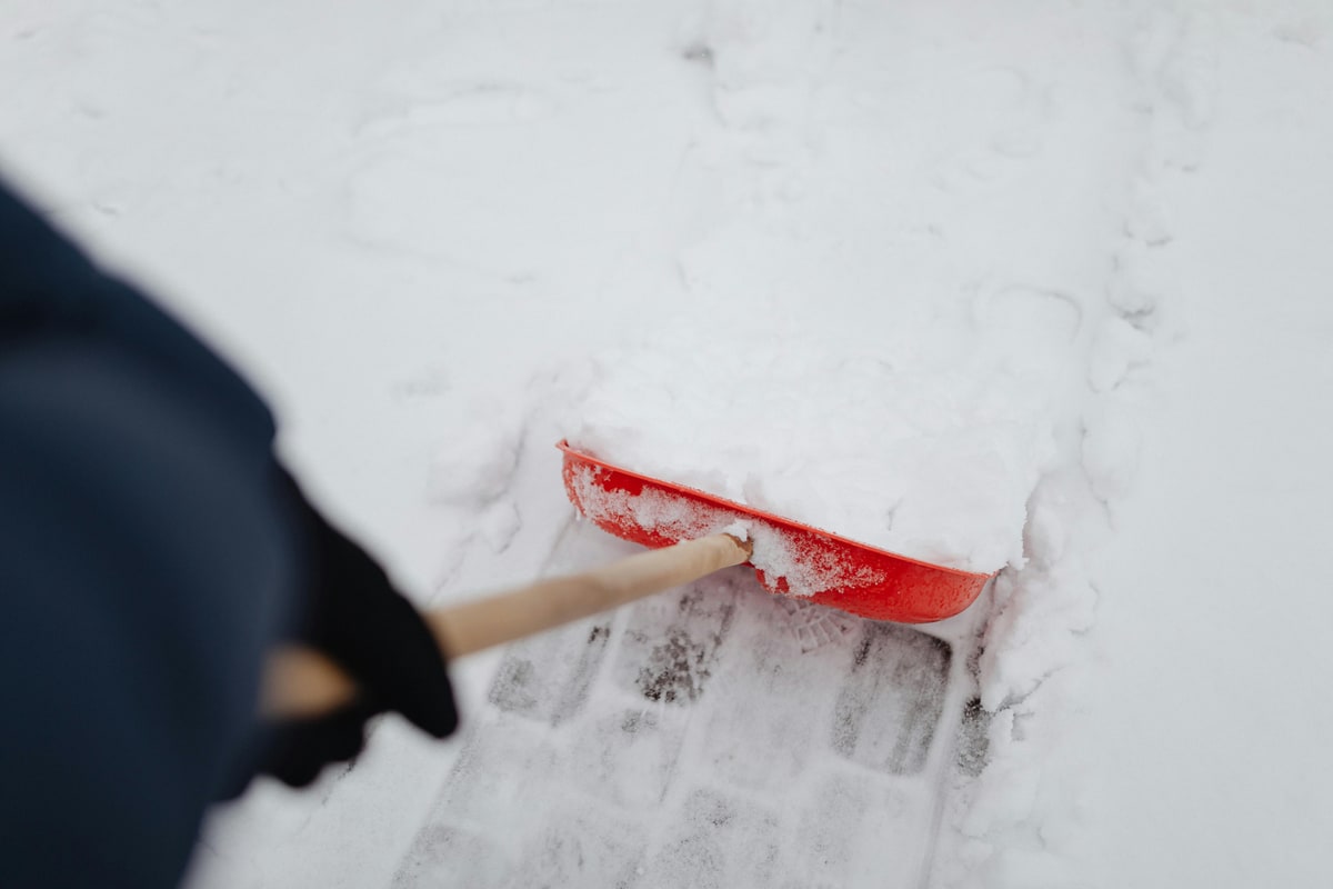 Schneeschaufel und Streumittel auf einem Gehweg — Symbolbild Räum- und Streupflicht im Winter